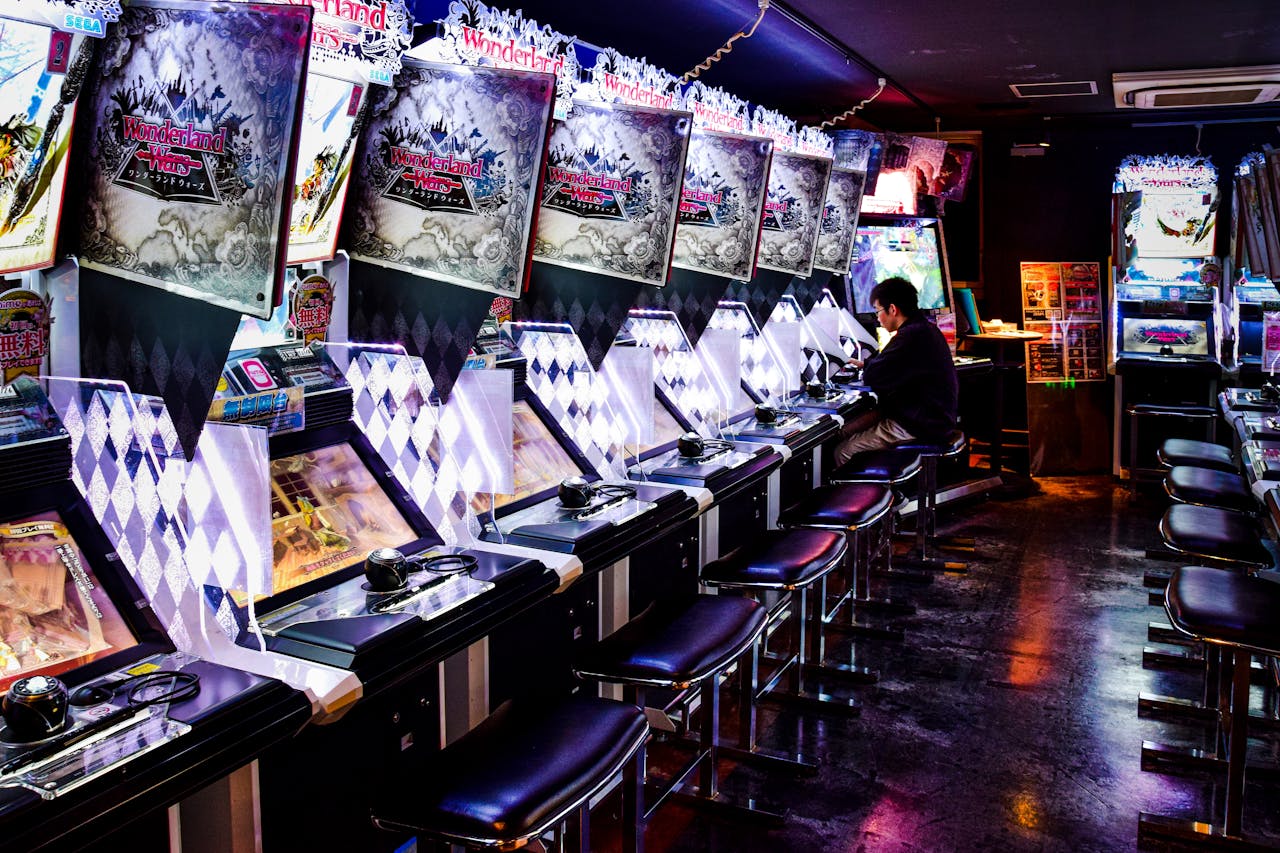 Home A man plays inside a modern arcade in Tokyo, illuminated by neon lights and gaming machines.
